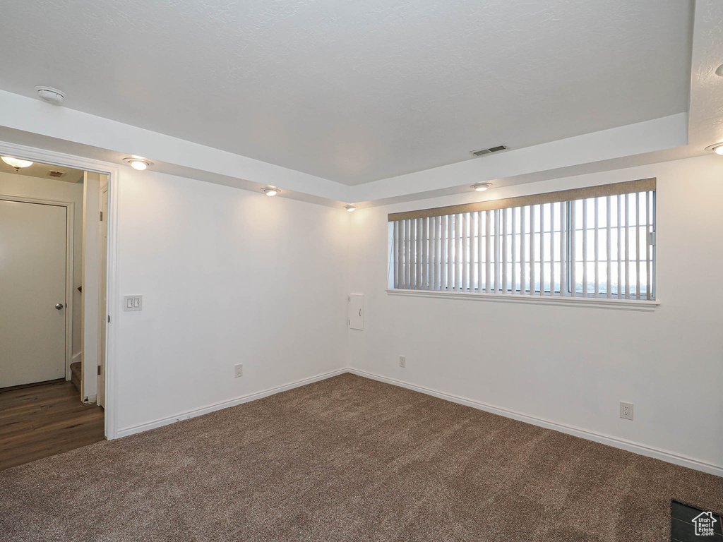Carpeted empty room with visible vents and baseboards