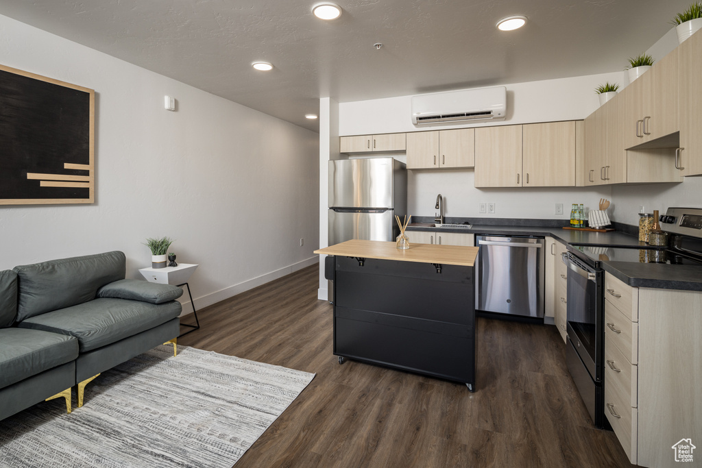 Kitchen with appliances with stainless steel finishes, dark wood-style flooring, a sink, a wall mounted air conditioner, and baseboards