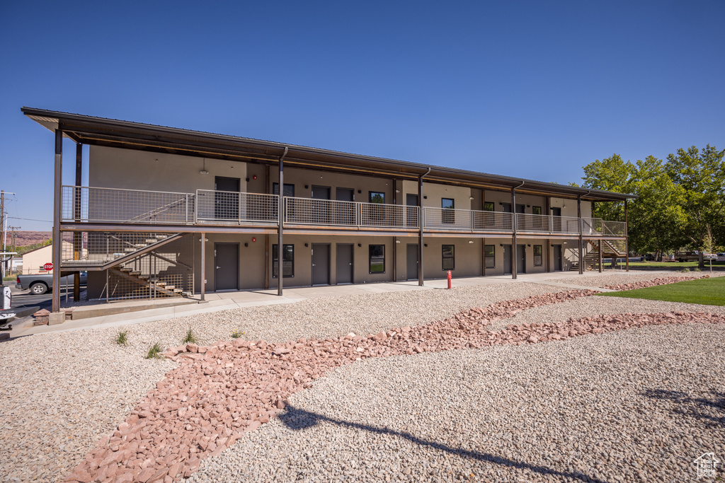 Rear view of property with a patio area, stairway, and stucco siding