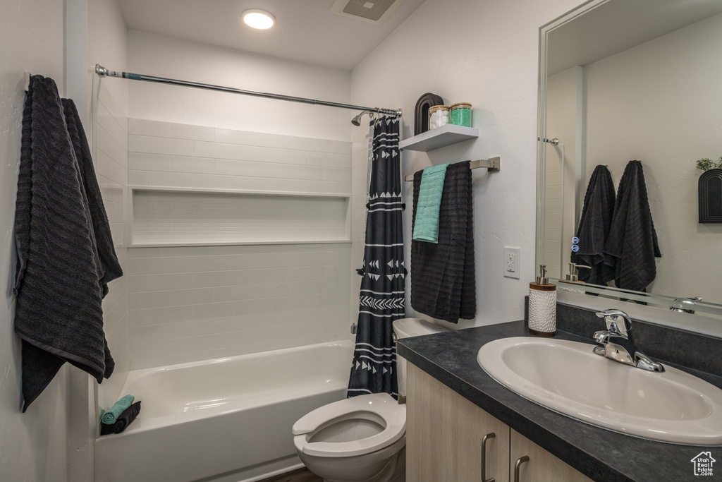 Bathroom with shower / tub combo, vanity, visible vents, and toilet