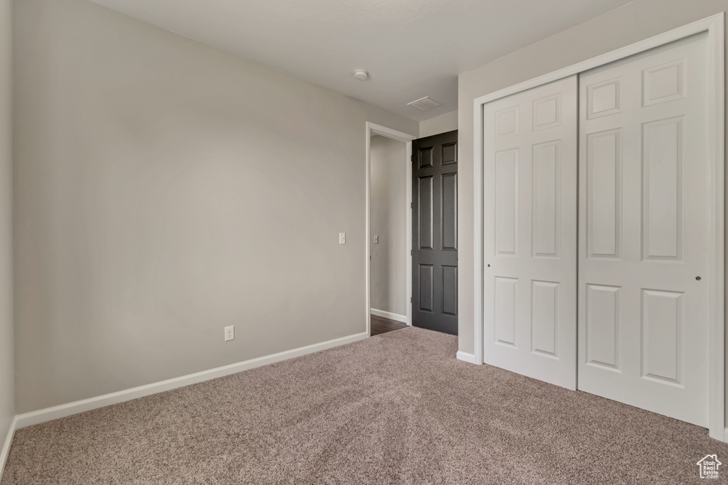 Unfurnished bedroom featuring carpet flooring, a closet, and baseboards
