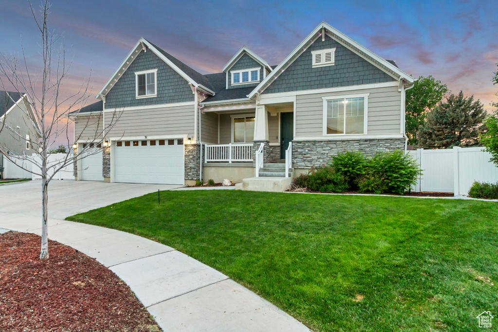 Craftsman house with covered porch, an attached garage, stone siding, and driveway