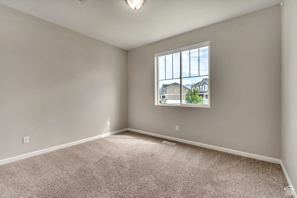 Carpeted spare room featuring baseboards