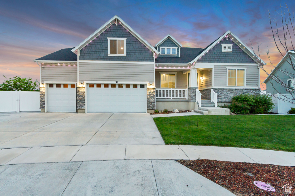 Craftsman inspired home with covered porch, stone siding, and driveway