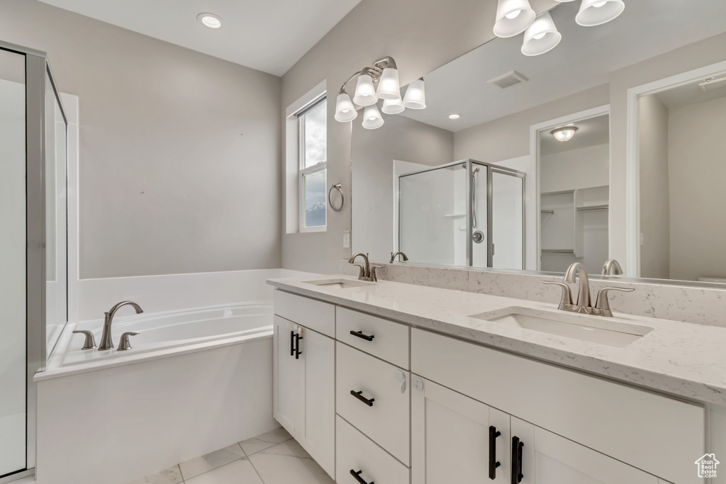 Full bath featuring a shower stall, a garden tub, double vanity, marble finish flooring, and a chandelier