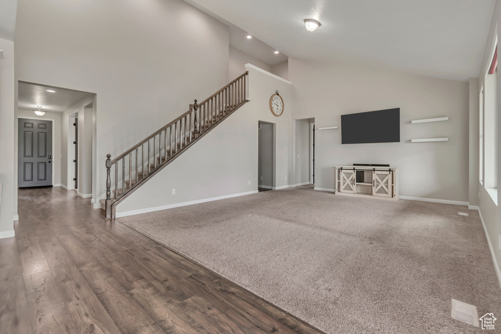 Unfurnished living room with high vaulted ceiling, stairway, baseboards, recessed lighting, and wood finished floors
