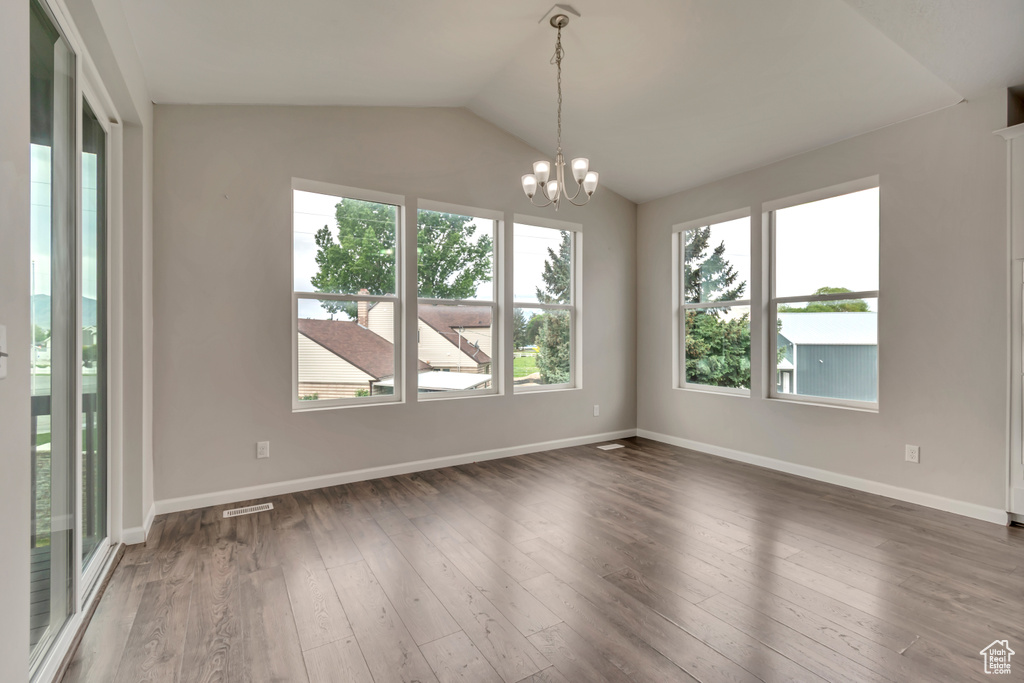 Unfurnished room with vaulted ceiling, a chandelier, wood finished floors, and baseboards