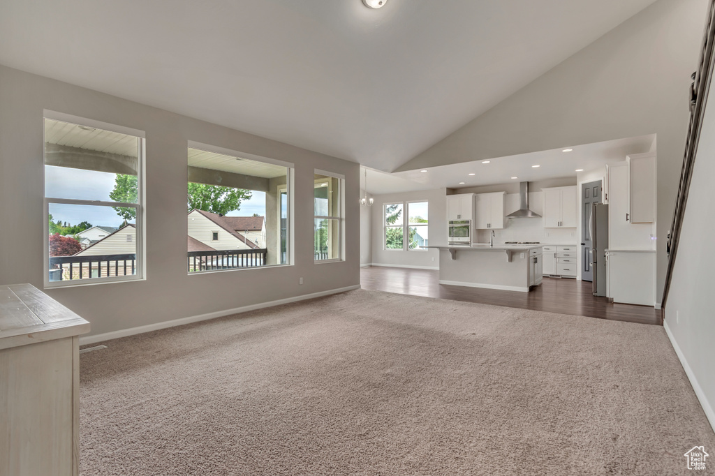 Unfurnished living room with dark carpet, baseboards, recessed lighting, and high vaulted ceiling