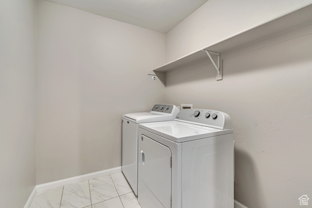 Laundry room with separate washer and dryer, light marble finish floors, and baseboards
