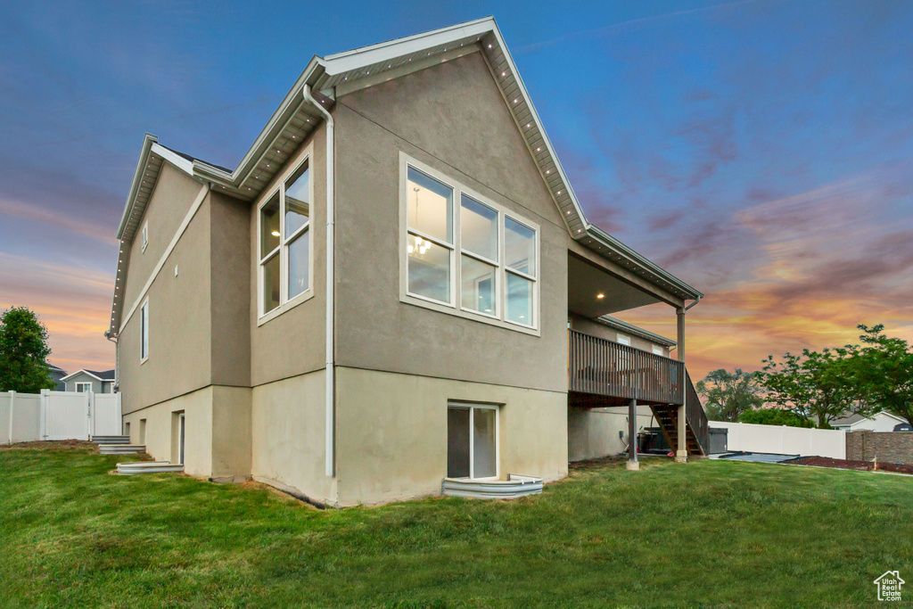 Back of house at dusk with stairs, stucco siding, and a deck