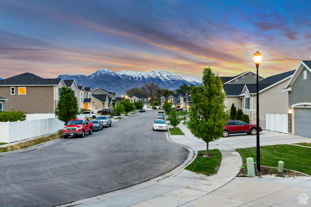 View of asphalt road featuring a residential view, sidewalks, a mountain view, and curbs