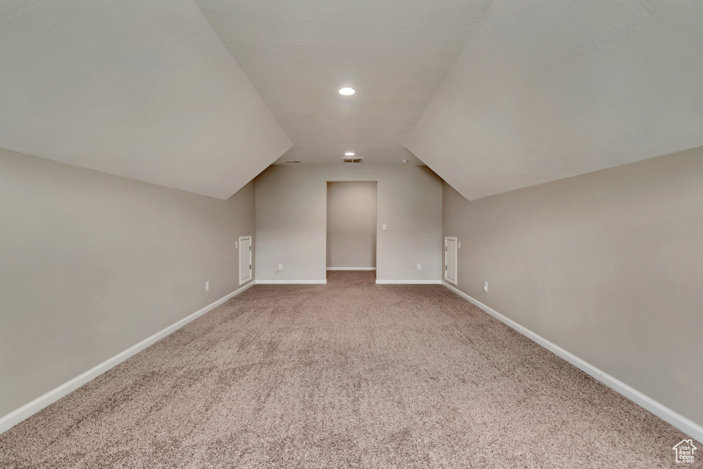 Bonus room with lofted ceiling, carpet, and baseboards