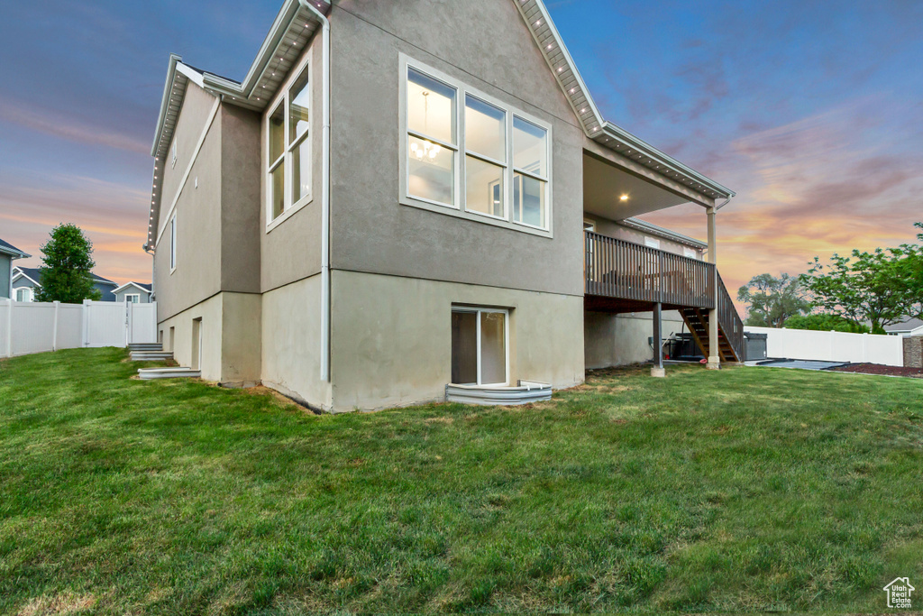Back of property at dusk featuring stairs, stucco siding, and a wooden deck