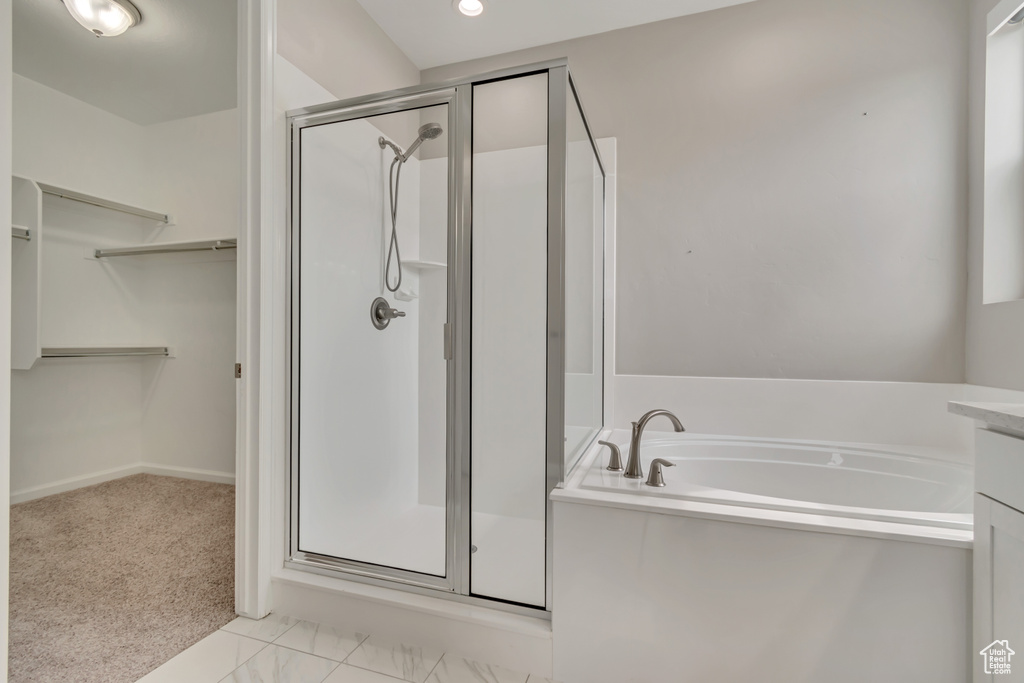 Bathroom with a stall shower, a spacious closet, a garden tub, and vanity