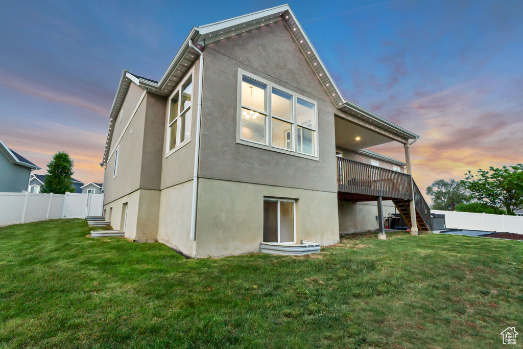 Back of property at dusk with stairs, stucco siding, and a wooden deck