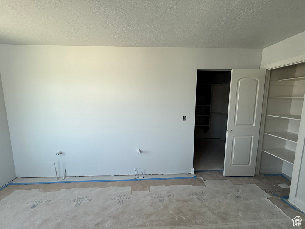 Unfurnished bedroom with a textured ceiling, a closet, and unfinished concrete floors