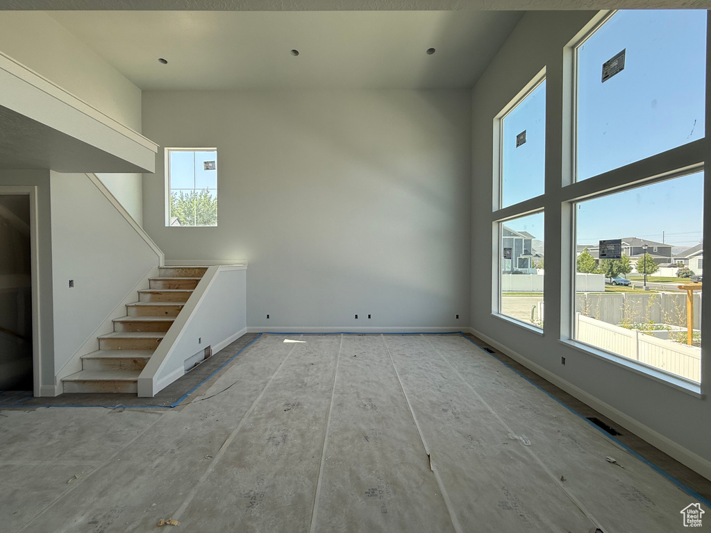 Unfurnished living room featuring healthy amount of natural light and stairway