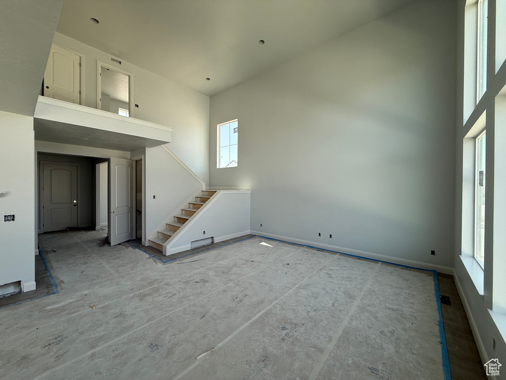 Unfurnished living room with a towering ceiling and stairs