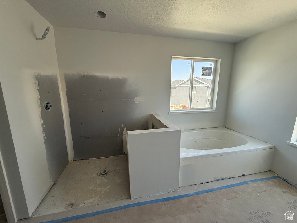 Full bath with a garden tub and a textured ceiling