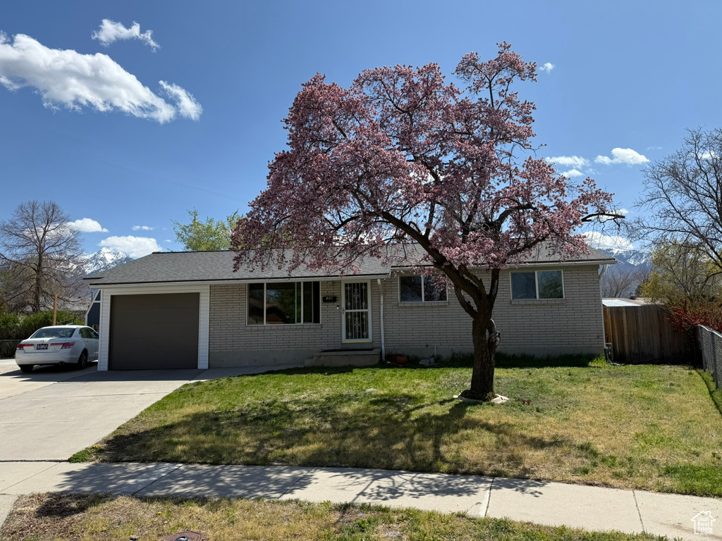 Ranch-style house with an attached garage, fence, brick siding, and concrete driveway