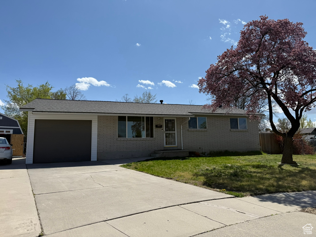 Single story home featuring a front lawn, concrete driveway, fence, a garage, and brick siding