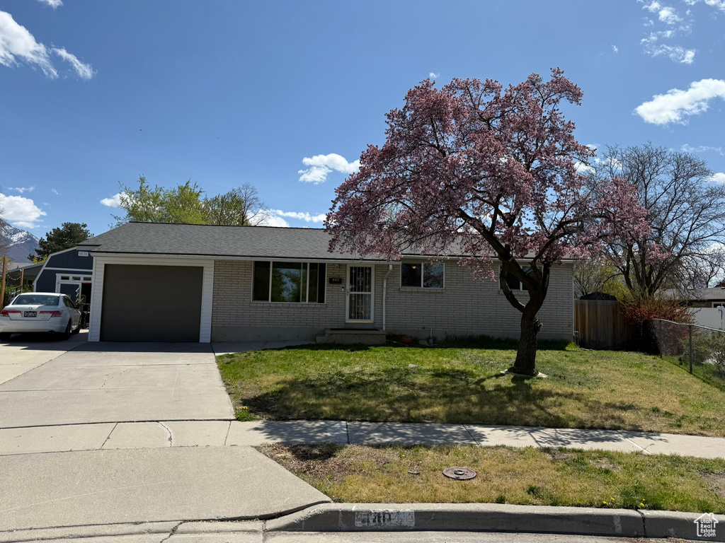 Single story home featuring driveway, an attached garage, fence, a front yard, and brick siding