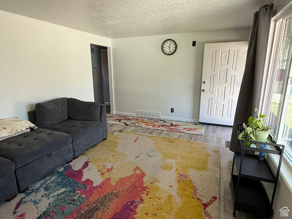 Living room featuring a textured ceiling, wood finished floors, visible vents, and baseboards