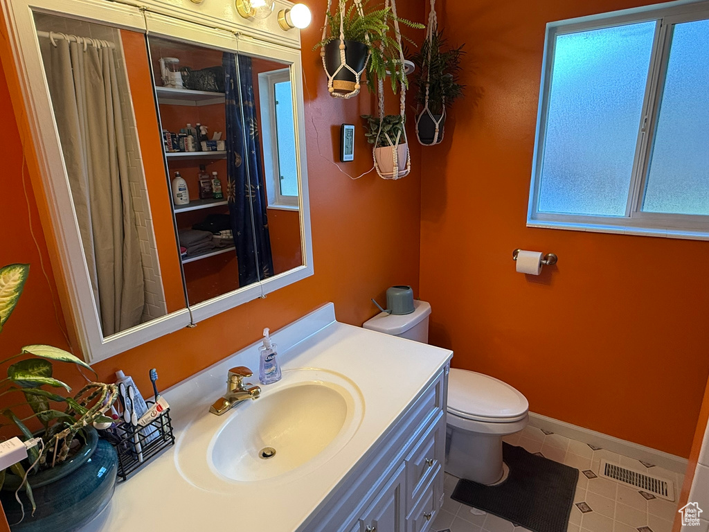 Bathroom with visible vents, baseboards, vanity, and toilet