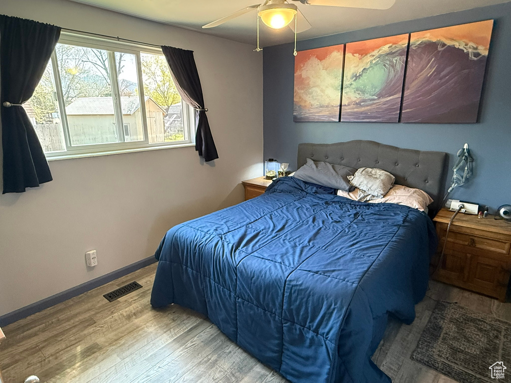 Bedroom with baseboards, wood finished floors, visible vents, and a ceiling fan