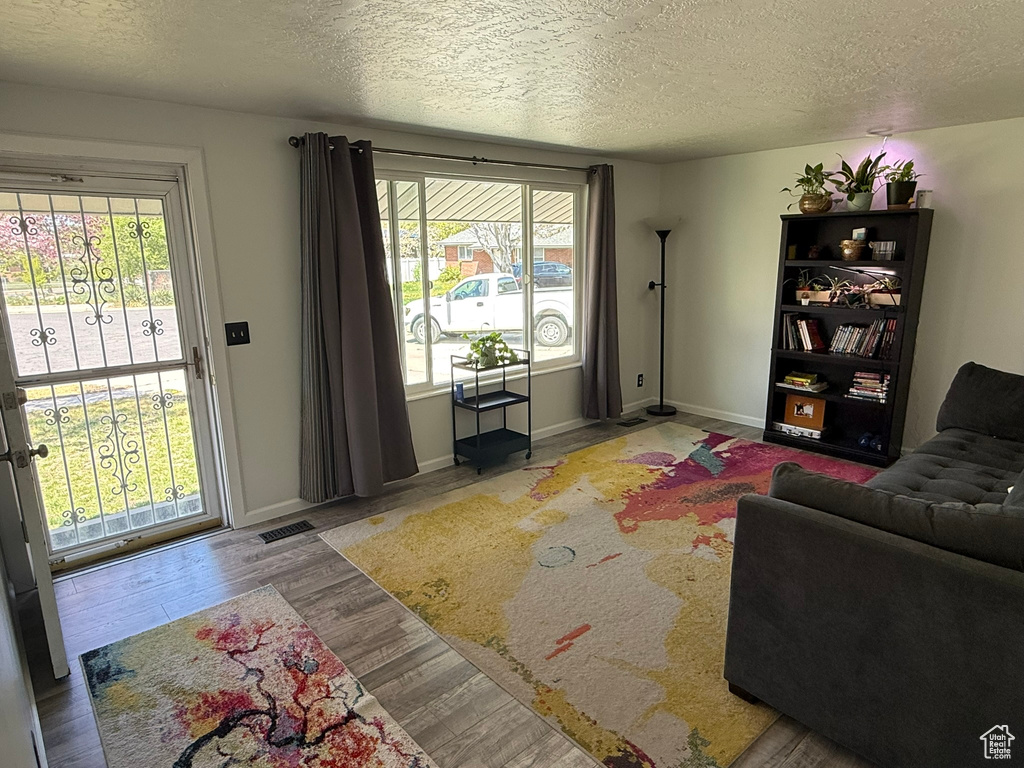 Living area with baseboards, wood finished floors, a textured ceiling, and visible vents