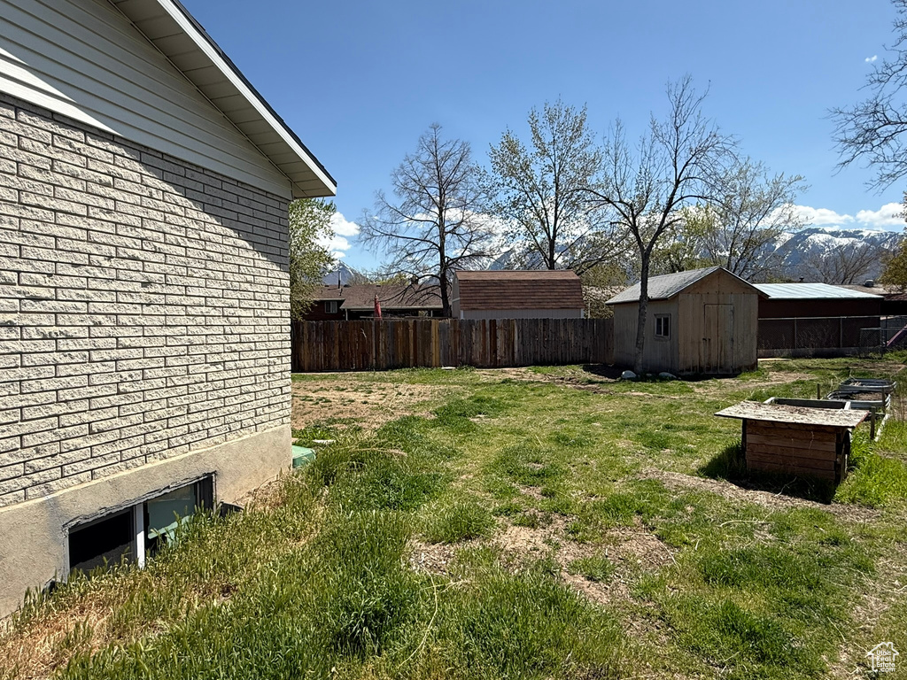 View of yard with fence, an outbuilding, and a storage shed