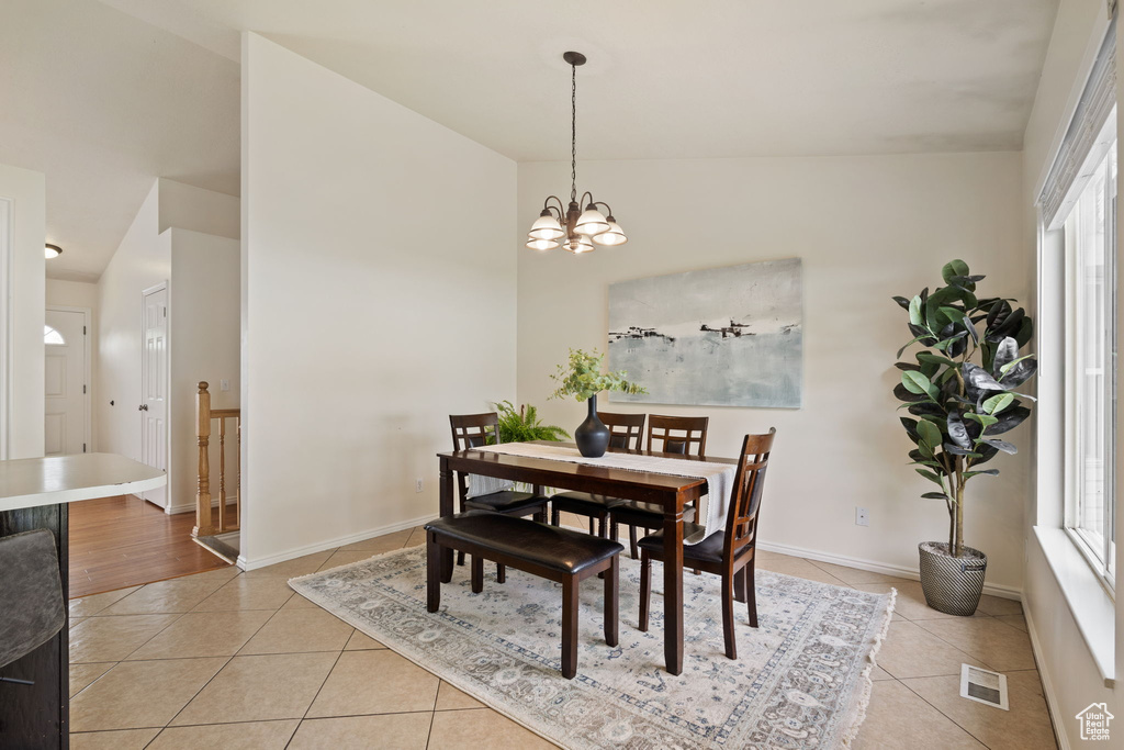 Dining area with a wealth of natural light, a notable chandelier, visible vents, and light tile patterned floors