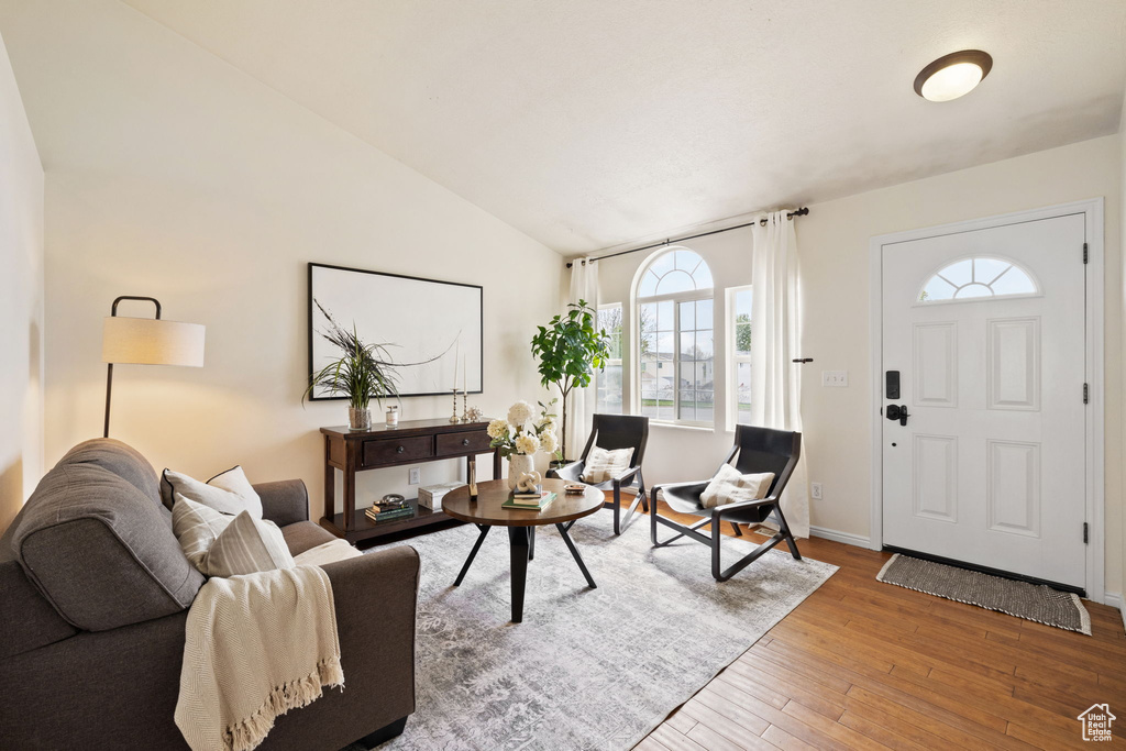 Living area featuring lofted ceiling, hardwood / wood-style floors, and baseboards
