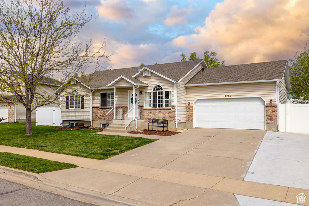 View of front facade with an attached garage, driveway, brick siding, and a front yard