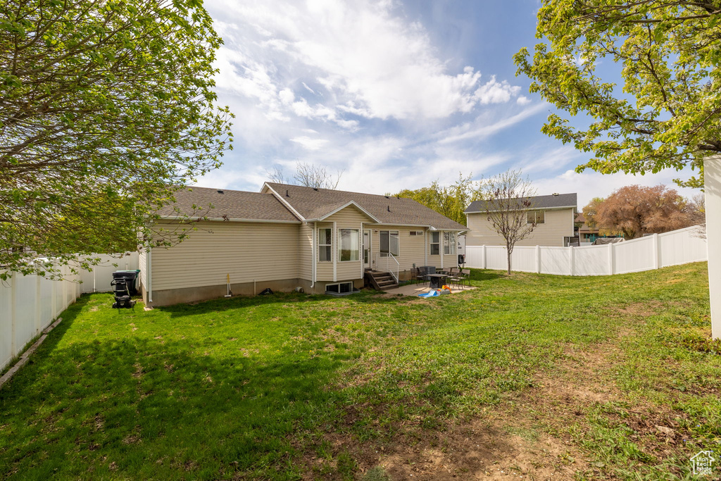 Back of property featuring a lawn, a patio, a fenced backyard, and entry steps