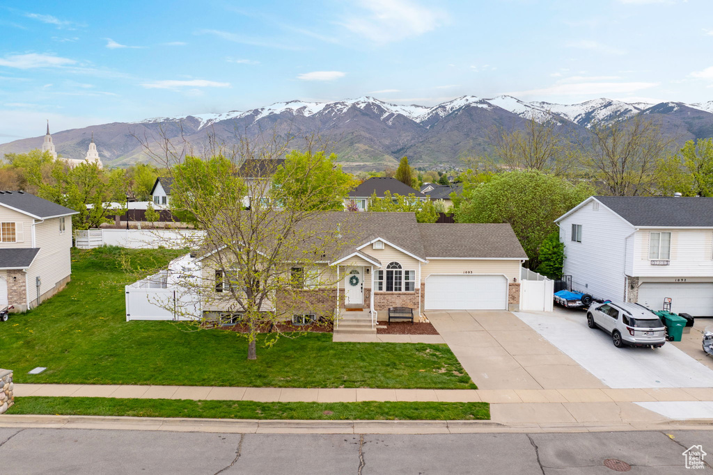 Ranch-style house featuring a garage, a front lawn, a mountain view, and concrete driveway