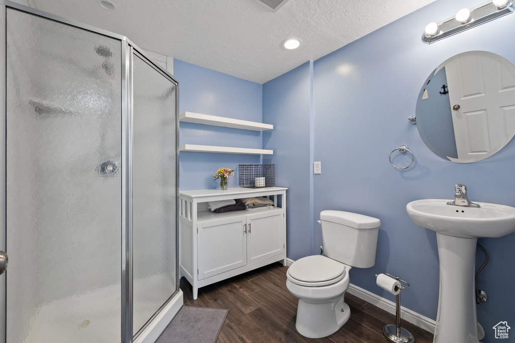 Full bath featuring toilet, a sink, wood finished floors, a stall shower, and baseboards