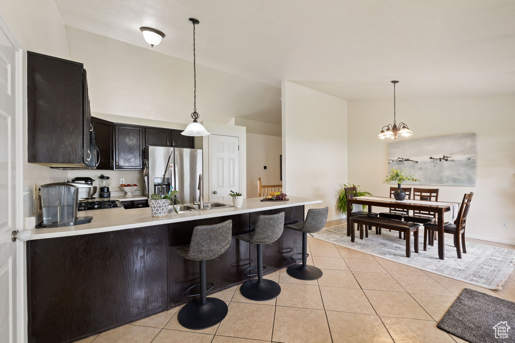 Kitchen with decorative light fixtures, a peninsula, stainless steel fridge with ice dispenser, and light countertops