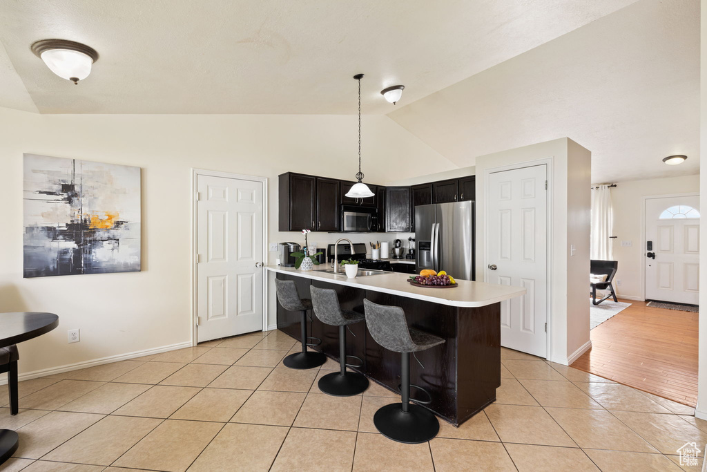 Kitchen featuring a kitchen breakfast bar, stainless steel fridge with ice dispenser, light countertops, light tile patterned floors, and a peninsula