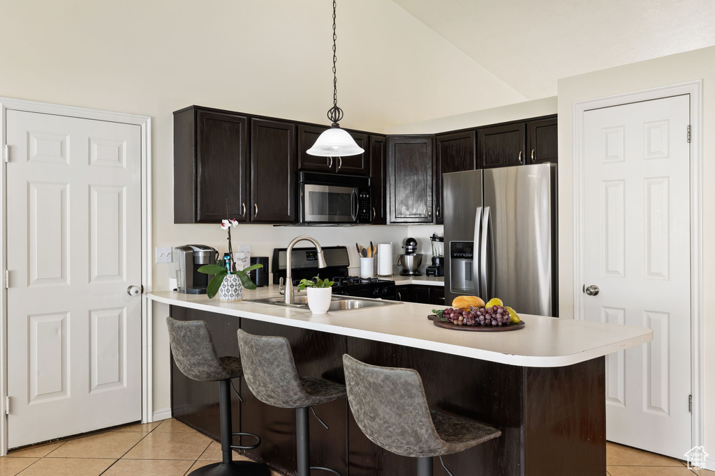 Kitchen featuring a kitchen breakfast bar, light tile patterned floors, stainless steel appliances, light countertops, and a peninsula