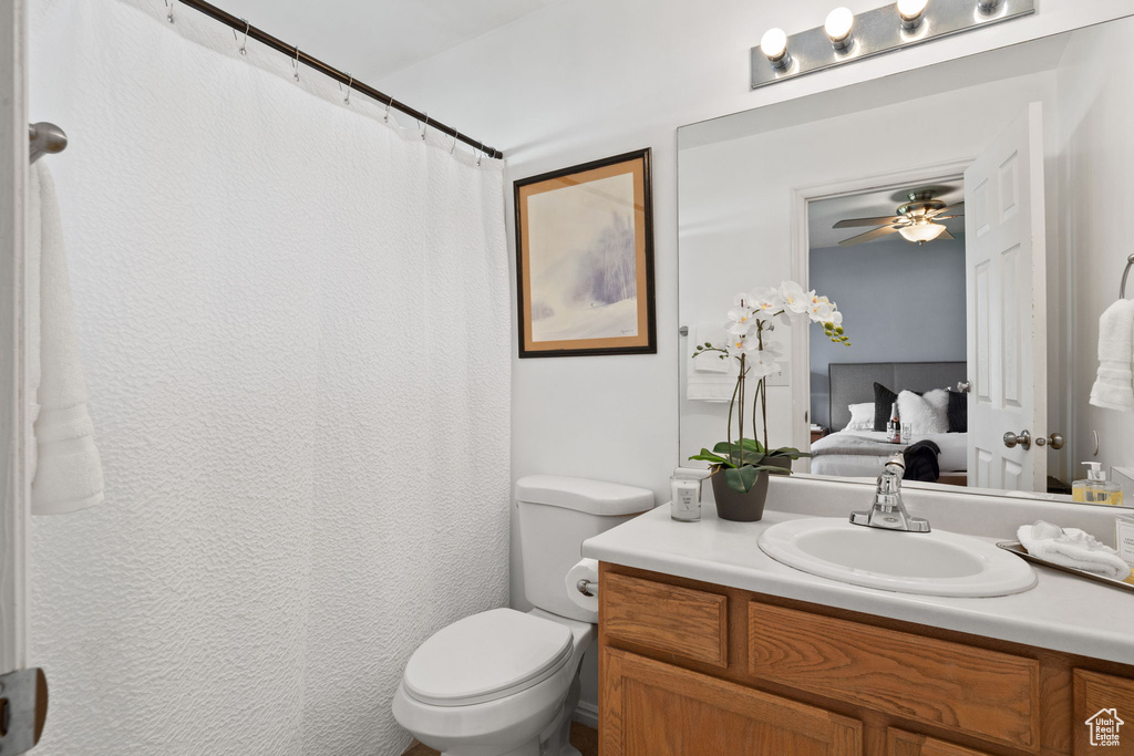 Ensuite bathroom with vanity, connected bathroom, ceiling fan, and toilet
