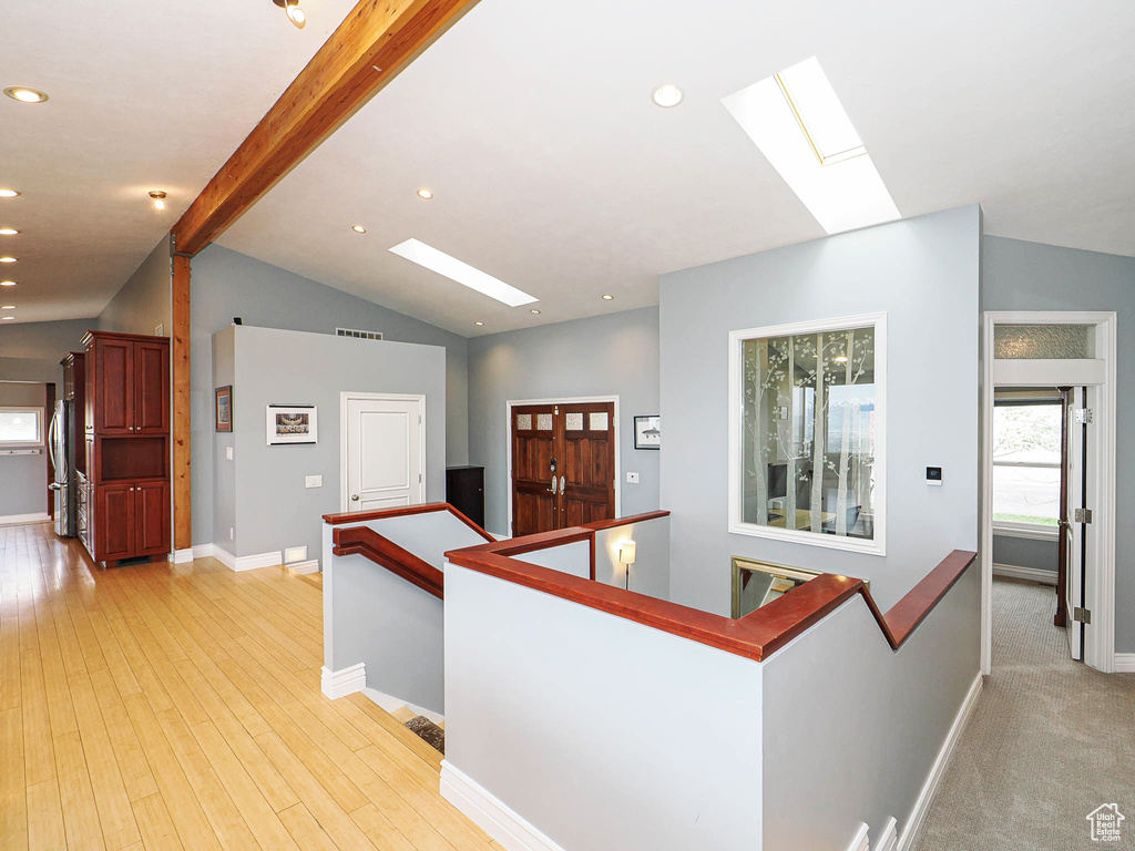 Hall with a skylight, an upstairs landing, baseboards, recessed lighting, and light wood finished floors