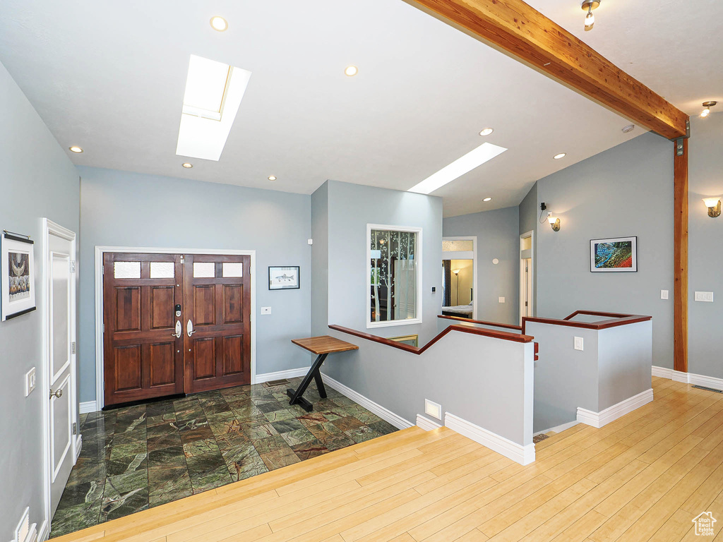 Foyer entrance with a skylight, recessed lighting, beamed ceiling, baseboards, and wood finished floors