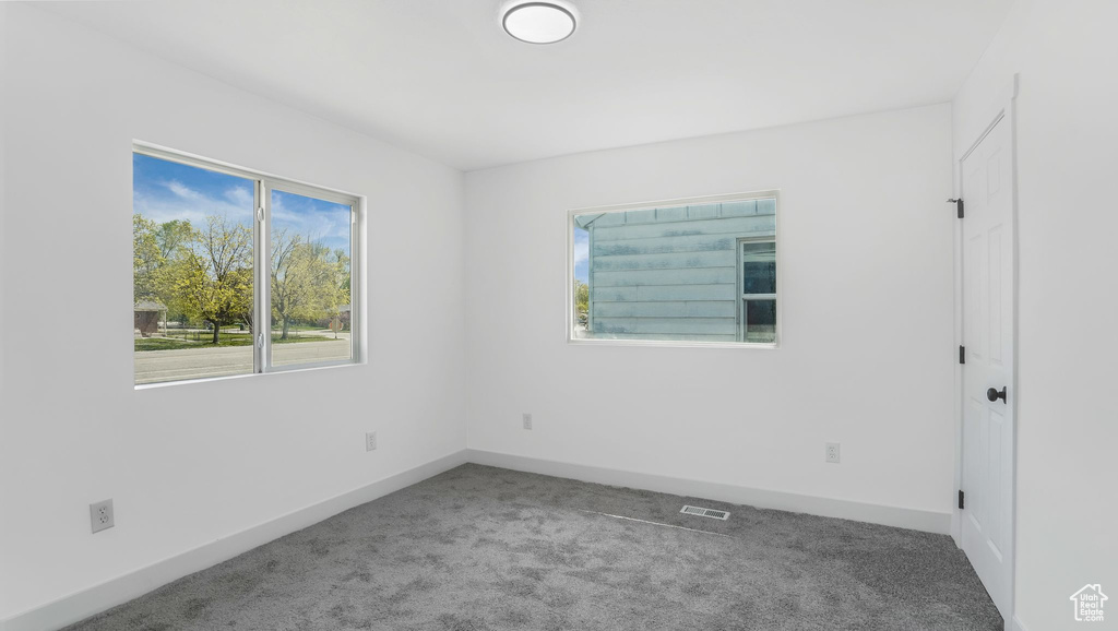 Spare room featuring visible vents, baseboards, carpet flooring, and a wealth of natural light