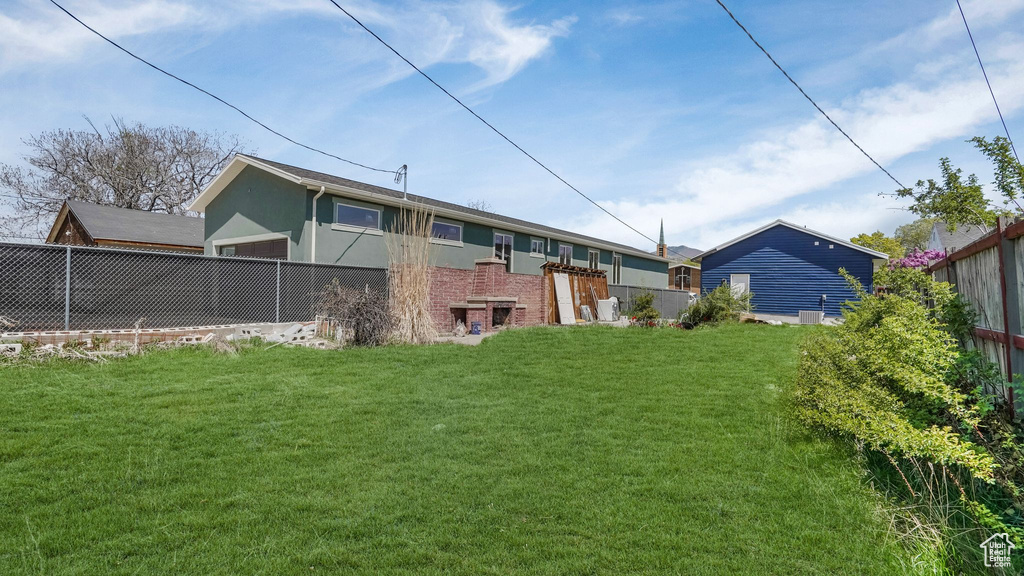 Back of house with a lawn, fence, and stucco siding