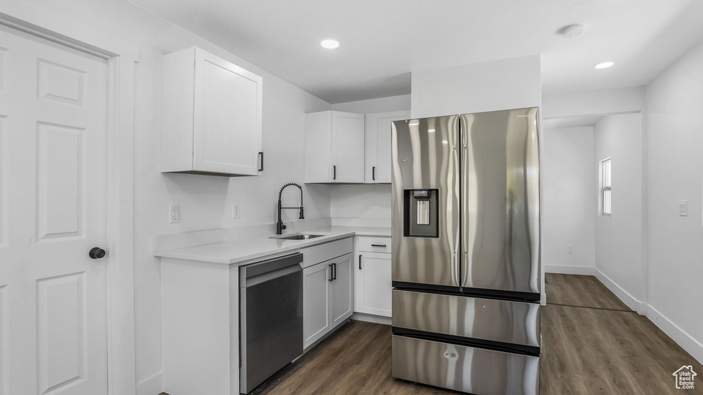Kitchen with white cabinets, appliances with stainless steel finishes, a sink, and light countertops