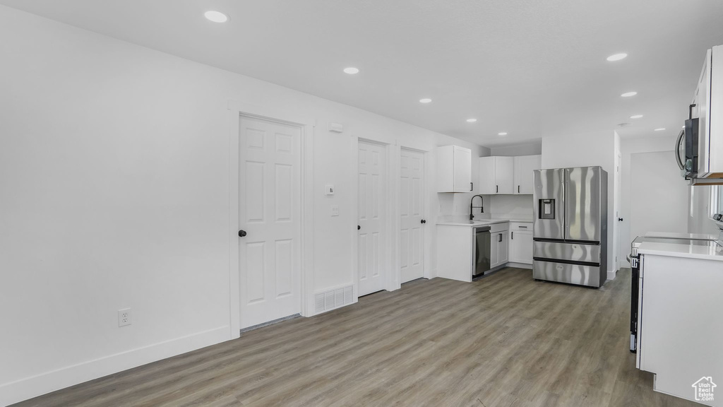Kitchen with a sink, light wood-style floors, stainless steel appliances, light countertops, and visible vents