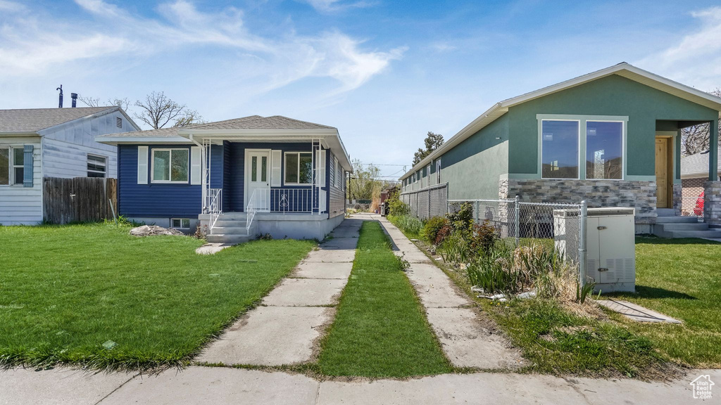 Exterior space with a front lawn, stone siding, central AC, covered porch, and fence