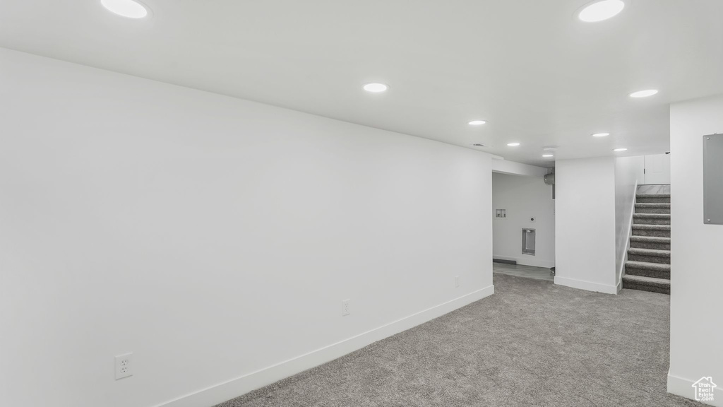 Finished below grade area featuring light carpet, baseboards, recessed lighting, and stairway