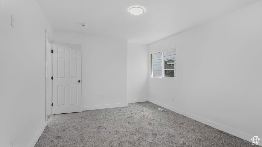 Carpeted spare room with visible vents and baseboards